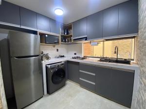 a kitchen with black cabinets and a stainless steel refrigerator at Refugio Nordico de 3 habitaciones inc Cochera en 2do piso in Trujillo