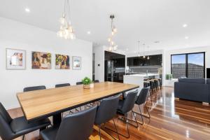 a dining room and kitchen with a wooden table and chairs at Bayview Luxe- Sleeping 14, Pet Friendly, Views- 4 bedroom, lounge with sofa beds in Curlewis