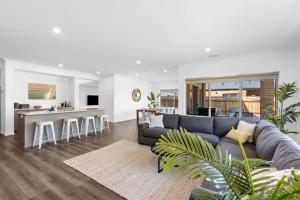 a living room with a couch and a kitchen at City & Surf Getaway in Grovedale