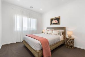 a bedroom with a bed with white walls and a window at City & Surf Getaway in Grovedale