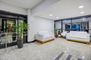 a lobby with two white chairs and windows at Hotel Domani in Guarulhos