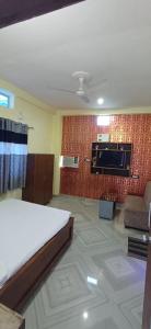 a room with a bed and a couch and a tv at Hotel relaxinn in Saharsa