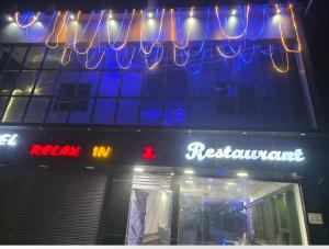 a restaurant with neon signs on the side of a building at Hotel relaxinn in Saharsa +1 photo