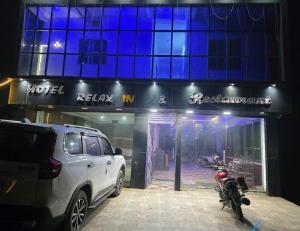 a car parked in front of a hotel with a motorcycle at Hotel relaxinn in Saharsa