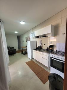 a kitchen with white appliances and a living room at Casa Dunas - Las Caracolas - Cassino RS in Rio Grande