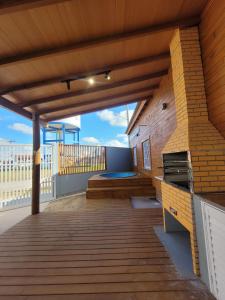a large wooden deck with a grill on a balcony at Casa Dunas - Las Caracolas - Cassino RS in Rio Grande +11 photos
