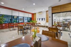 a restaurant with tables and chairs and a cafeteria at Hotel Domani in Guarulhos
