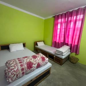 a room with two beds and a window with pink curtains at Briddhim Guest House in Syābru Bensi