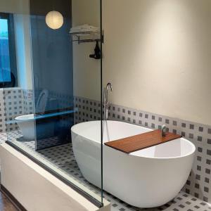 a bath tub in a bathroom with a glass shower at Casa de Holu Homestay in Ða Gia