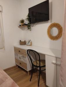 a desk with a television on a wall with a chair at Coté Lac mini in Mimizan