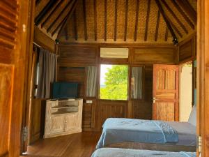 a bedroom with a bed and a tv and a window at Villa Bakso Mentigi in Teluknarat