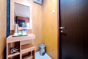 a bathroom with a wooden door and a mirror at Urbanview Hotel Salakview Megamendung in Pondok Cipaseban +32 photos