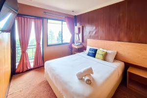 a bedroom with a large bed with a large window at Urbanview Hotel Salakview Megamendung in Pondok Cipaseban