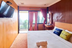 a bedroom with a bed with a television on a wall at Urbanview Hotel Salakview Megamendung in Pondok Cipaseban