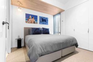a bedroom with a large bed with blue pillows at Mod House Ocean Grove- Walk to the shops, cafes, beach and park! Brand new luxury apartment in gated complex in Ocean Grove