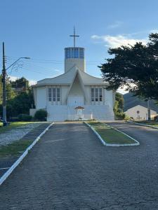 a church with a cross on top of a road at Kit Net in Governador Celso Ramos
