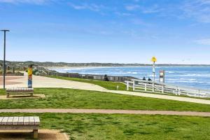 a park with benches and the ocean in the background at Mod House Ocean Grove- Walk to the shops, cafes, beach and park! Brand new luxury apartment in gated complex in Ocean Grove