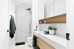 a white bathroom with a toilet and a sink at Mod House Ocean Grove- Walk to the shops, cafes, beach and park! Brand new luxury apartment in gated complex in Ocean Grove +20 photos