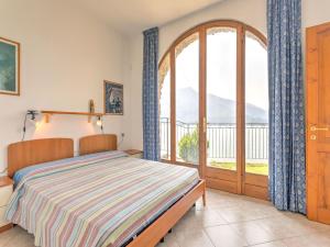 a bedroom with a bed and a large window at Wonderful flat with swimming pool, lift and garden in Gravedona