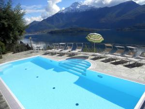 a swimming pool with chairs and a view of a mountain at Wonderful flat with swimming pool, lift and garden in Gravedona