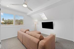 a living room with a couch and a flat screen tv at Beach Street - Town Location - Stone Real Estate Yamba in Yamba