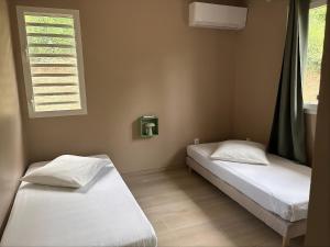 two beds sitting in a room with a window at Évasion Caraïbes in Ducos