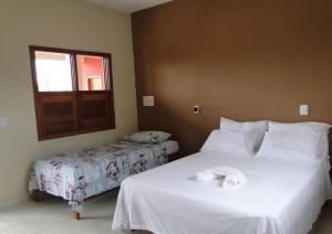 a hotel room with two beds and a window at Pousada Flores in Itaúnas