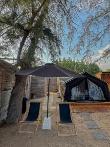 two chairs and an umbrella in front of a tent at Coody Seastar in Ban U Taphao