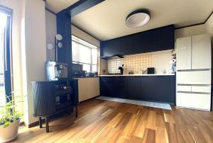 a large kitchen with black cabinets and a wooden floor at Villa Nami in Kashima