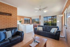 a living room with two leather couches and a kitchen at Elsewhere 3- Town Location - Stone Real Estate Yamba in Yamba