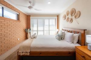 a bedroom with a large bed and a brick wall at Elsewhere 3- Town Location - Stone Real Estate Yamba in Yamba +20 photos