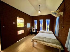a bedroom with a bed with blue curtains and a table at บ้านสวนบรรจงอักษร Bansuan Banjong Akkson in Rayong