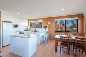 a kitchen with white appliances and a table with chairs at Elsewhere 3- Town Location - Stone Real Estate Yamba in Yamba