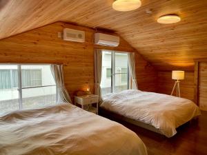 a bedroom with two beds in a room with wooden walls at Asu base Yuge in Hachimantai