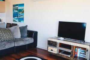 a living room with a couch and a flat screen tv at Seaspray 8 - Ocean Views - Stone Real Estate Yamba in Yamba