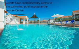 a swimming pool with blue chairs and a fountain at Seaspray 8 - Ocean Views - Stone Real Estate Yamba in Yamba