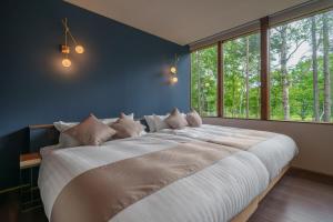 ein großes Bett in einem Schlafzimmer mit einem großen Fenster in der Unterkunft Noah Rusutsu in Rusutsu