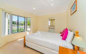 a bedroom with a white bed and a window at Oceania Cottage- Pet Friendly -Stone Real Estate Yamba in Yamba