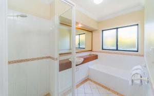 a bathroom with a tub and a sink and a shower at Oceania Cottage- Pet Friendly -Stone Real Estate Yamba in Yamba +7 photos