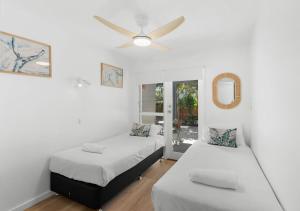 a bedroom with two beds and a ceiling fan at Pippi Sands - Pet Friendly - Stone Real Estate in Yamba +11 photos