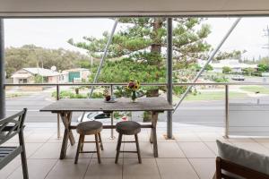 a table on a balcony with a view of a street at Six River - Town Location - Stone Real Estate Yamba in Yamba