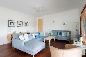 a living room with a blue couch and a table at Six River - Town Location - Stone Real Estate Yamba in Yamba