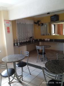 a kitchen with two tables and chairs and a counter at Hotel center Ribeirão in Ribeirão Preto