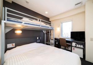 a bedroom with a bed and a desk and bunk beds at Super Hotel Asahikawa in Asahikawa