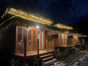 a resort cabin with a thatched roof at night at Morgans Bungalows in Maluk