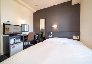 a hotel room with a bed and a desk with a computer at Super Hotel Asahikawa in Asahikawa