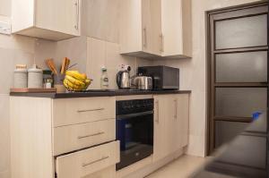 a kitchen with white cabinets and a black oven at MbaliBliss in Bulawayo