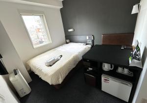 a small bedroom with a bed and a table at Super Hotel Asahikawa in Asahikawa +83 photos