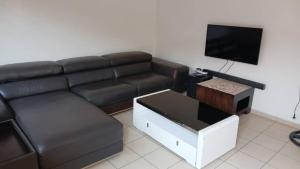 a living room with a black couch and a tv at Nkandla Resort in Bulawayo