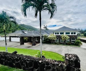 a house with a palm tree and a stone wall at Hale Halai in Hauula